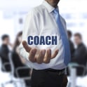 Elegant businessman holding the word coach in front of a business team